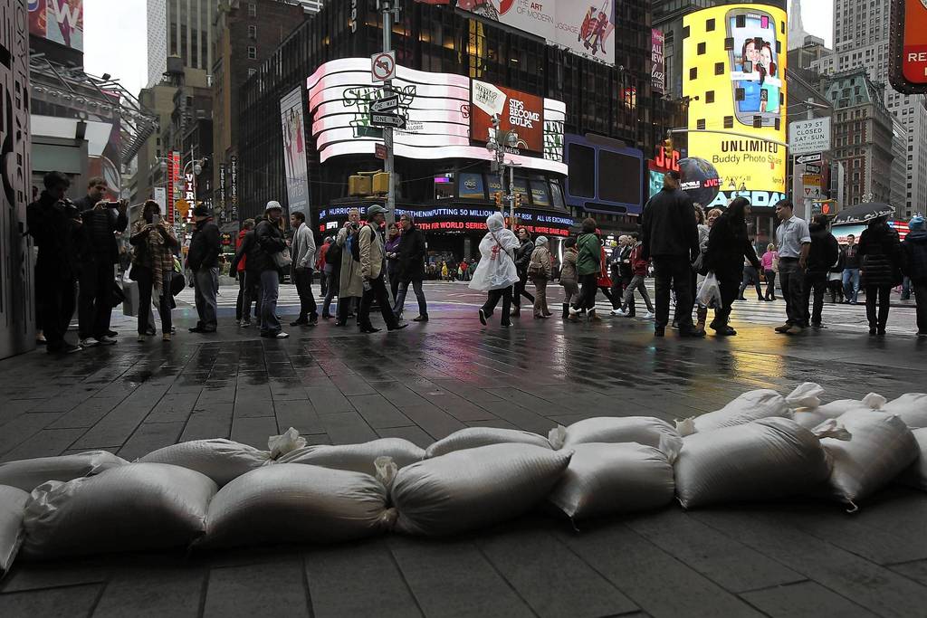 People walk by sand bags in front of a building in Times Square as Hurricane Sandy begins to affect New York City. The storm, which threatens 50 million people in the eastern third of the U.S., is expected to bring days of rain, high winds and possibly heavy snow. New York Governor Andrew Cuomo announced the closure of all New York City will bus, subway and commuter rail service as of Sunday evening.