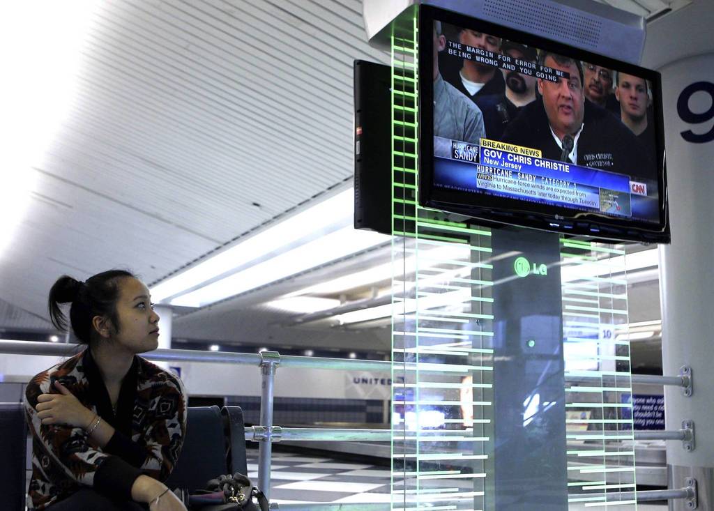 Seattle resident Navy Duong watches hurricane coverage on the East Coast on the baggage claim level of O'Hare International Airport. Duong was headed to New York on Monday to see family, but her flight has been delayed until Wednesday, stranding her in Chicago.