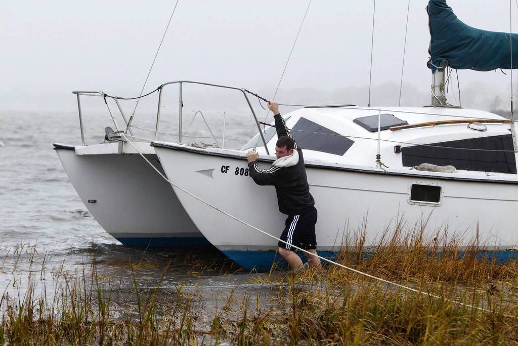 A man struggles to secure his boat near a marsh after breaking off its mooring and beaching itself during the effects of Hurricane Sandy in Quincy, Massachusetts. The monster storm bearing down on the East Coast, strengthened on Monday after hundreds of thousands moved to higher ground.