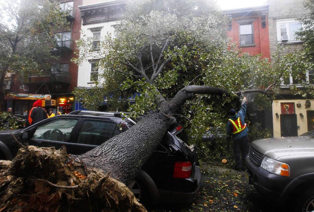 A workman cuts a tree in pieces after it fell on top of a car in Hoboken, New Jersey. Hurricane Sandy, one of the biggest storms ever to hit the United States, battered the densely populated East Coast, shutting down transportation, forcing evacuations in flood-prone areas and interrupting the presidential election campaign.