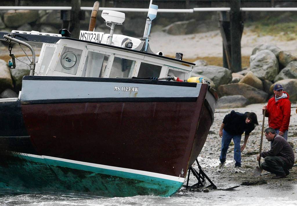 Men try to save a boat which became unmoored and washed up on shore due to high winds from Hurricane Sandy in Scituate, Massachusetts.