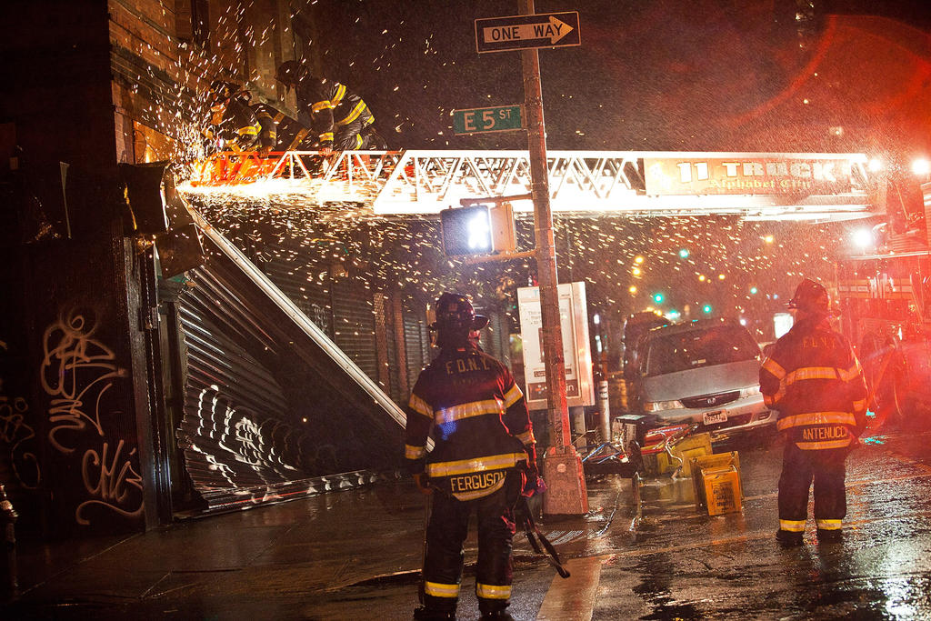 Firefighters use a saw in an attempt to remove a partially collapsed door due to Hurricane Sandy on October 29, 2012, in New York.
