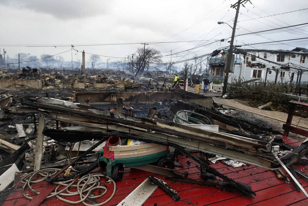 Homes that devastated by fire and the effects of Hurricane Sandy smolder at the Breezy Point section of the Queens borough of New York.
