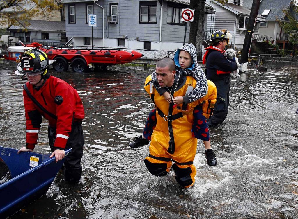 A rescue worker carries a boy on his back as emergency personnel rescue residents from flood waters brought on by Hurricane Sandy in Little Ferry, New Jersey.