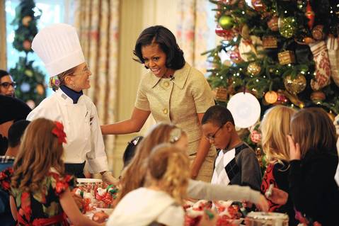 First lady Michelle Obama smiles as children do crafts, during the first viewing of the 2012 holiday decorations at the White House in Washington, DC.