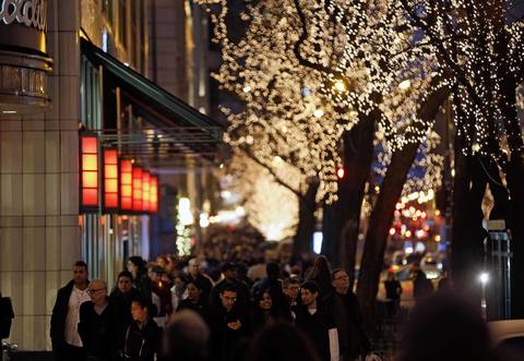 People walk along Michigan Avenue in downtown Chicago, illuminated by the street's holiday lights.