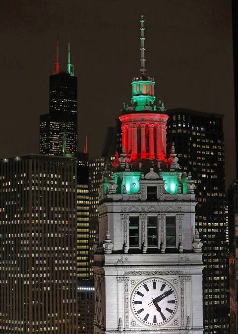 The Wrigley Building, foreground, which is located on Michigan Avenue, and the distant Willis Tower, background, are both illuminated with holiday lights.