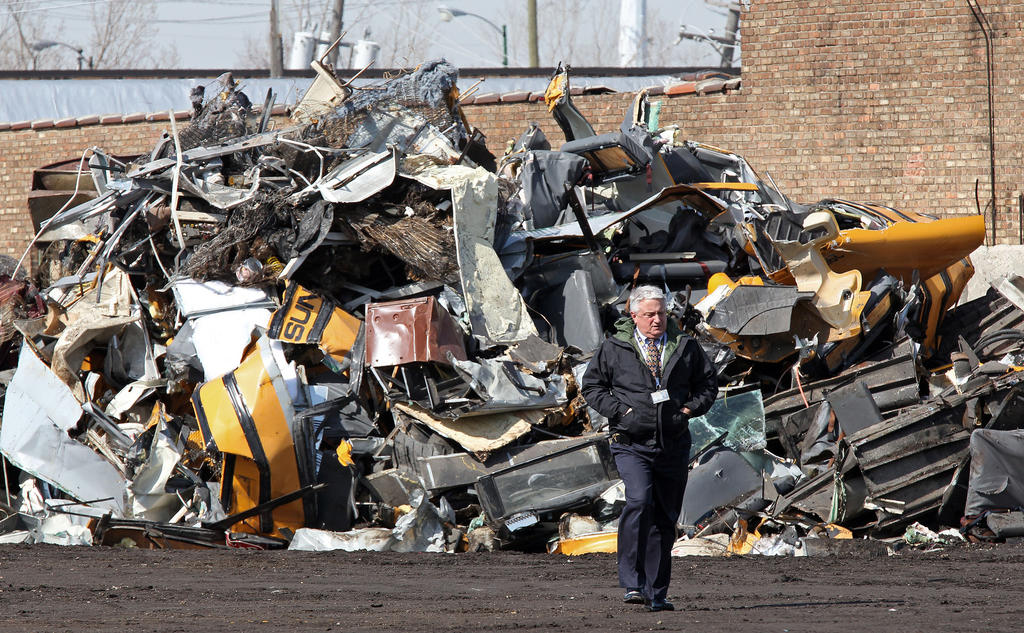 A police investigator walks past a pile of bus remnants at SRV Metal Scrapper at 3405 S. Lawndale Ave., on Friday. Buses were reported missing by Sunrise Transportation Thursday night.