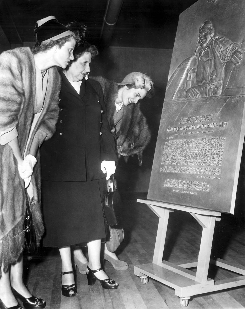 Mrs. Selma O'Hare, middle, and her daughters Mrs. Walter Palmer, left, and Mrs. Philip Tovrea, right, read the inscription on the bronze plaque commemorating the heroism of their son and brother Edward 