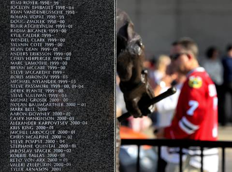 A Blackhawks fan takes in a statue honoring franchise players for a 25th anniversary monument.
