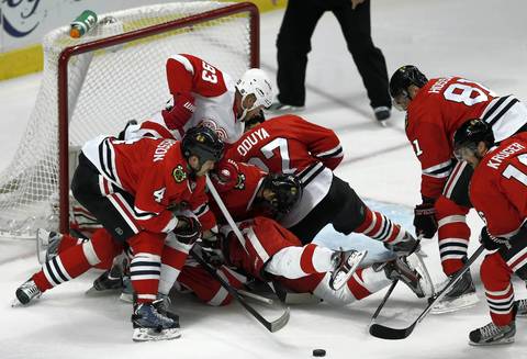 Five Blackhawks aid goalie Corey Crawford in making a save on a shot by the Red Wings' Johan Franzen in the first period.