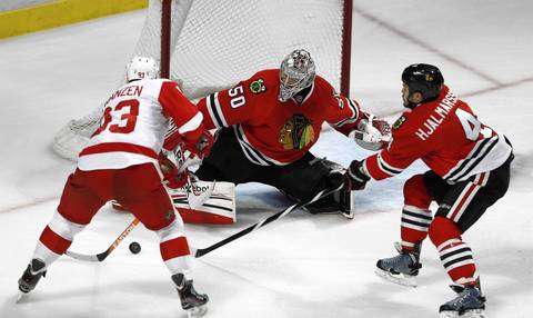 Corey Crawford and Niklas Hjalmarsson team up to defend against the Red Wings' Johan Franzen.