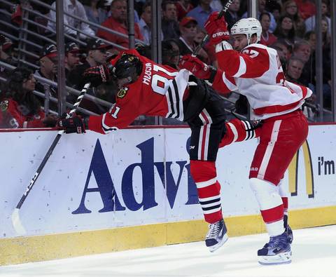 The Red Wings' Kyle Quincey knocks Marian Hossa into the boards in the first period.