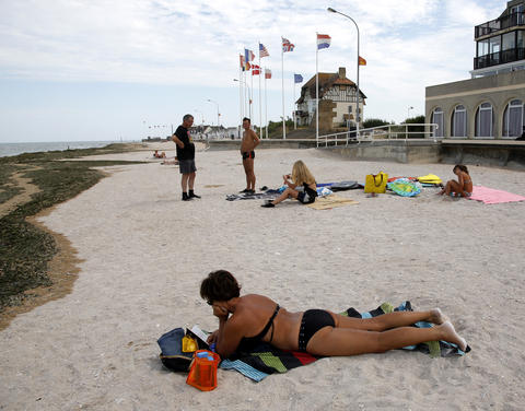A tourist sunbathes on a former Juno Beach landing area where Canadian troops came ashore on D-Day at Bernieres Sur Mer, France, August 23, 2013.