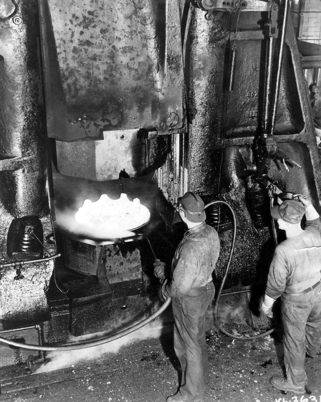 Hammers, striking a blow of 56,000 tons, are being used at Chrysler Corporations Dodge Chicago Aircraft Engine Plant to forge crankcase sections for the huge B-29 engines on Oct. 20, 1944. Shown above is the bottom part of a forge hammer forming one of these crankcases. Expert workmen control the force by a small foot pedal. The crankcases are then assembled into an 18 cylinder, 2200 horsepower, Wright air-cooled radial engine.