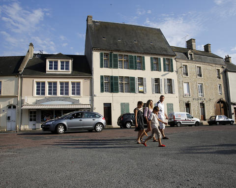 Tourists walk across the main square of Place Du Marche near the former D-Day landing zone of Omaha Beach, in Trevieres, France August 23, 2013.