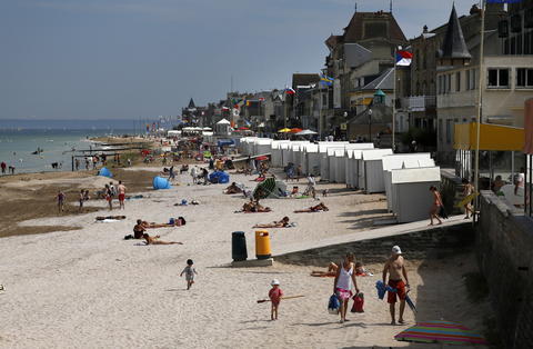 Tourists enjoy the sunshine on the former Juno Beach D-Day landing zone, where Canadian forces came ashore, in Saint-Aubin-sur-Mer, France, August 23, 2013. British and Canadian troops battled reinforced German troops holding the area around Caen for about two months following the D-Day landings in Normandy in 1944.