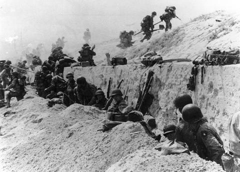 U.S. Army soldiers of the 8th Infantry Regiment, 4th Infantry Division, move out over the seawall on Utah Beach after coming ashore in front of a concrete wall near La Madeleine, France, June 6, 1944.