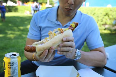Hubert Kim of Washington D.C., enjoys a foot long Polish sausage at Blues Fest in Grant Park.