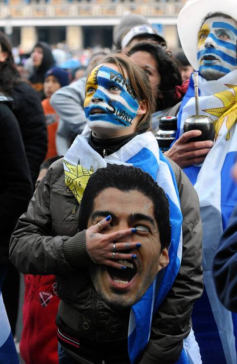 A fan of Uruguay, holding a Luis Suarez mask, sings the national anthem during the live broadcast of the FIFA World Cup Round of 16 match Brazil vs Uruguay in Montevideo.