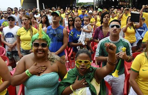 Brazilians sing the national anthem as they watch the FIFA World Cup 2014 Round of 16 match between Brazil and Chile at bar "Toa Toa" in Porto Seguro, Brazil.