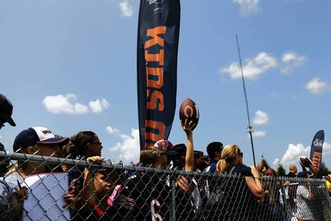 A young Bears fan holds up a ball for an autograph from a player at training camp.