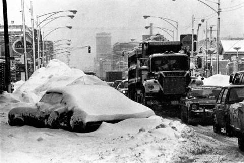 Chicago continues the battle against a huge snowstorm as a truck passes a car covered with snow from the great blizzard at Lawrence Avenue and Clark Street on Jan. 24, 1979.