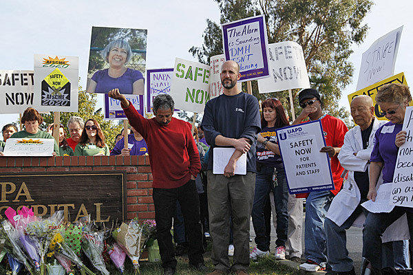 A moment of silence is observed as workers at Napa State Hospital remember Donna Gross, a psych tech pictured on sign, who was killed by a patient. Nearly 200 assembled at the entrance to for safer conditions at the hospital. (Robert Gauthier / Los Angeles Times)