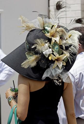 A spectator walks through the paddock with her floral fancy hat.