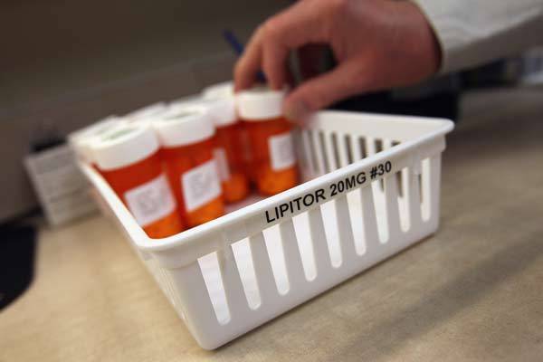 A pharmacist takes a bottle of cholesterol-reduction medication while filling prescriptions at a community health center