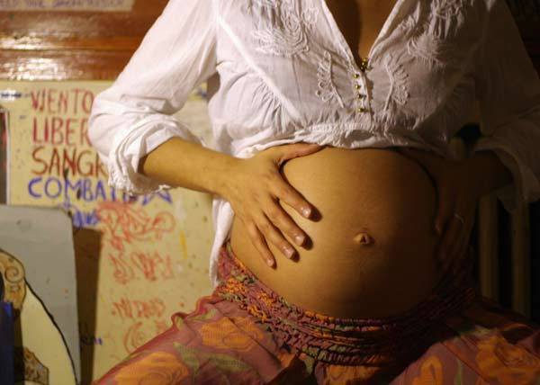 An eight-month pregnant woman touches her stomach
