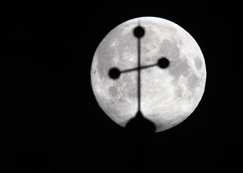 The super moon is pictured behind the cross of a church in Vienna June 23, 2013. The largest full moon of the year called the "super moon" will light up the night sky this weekend.