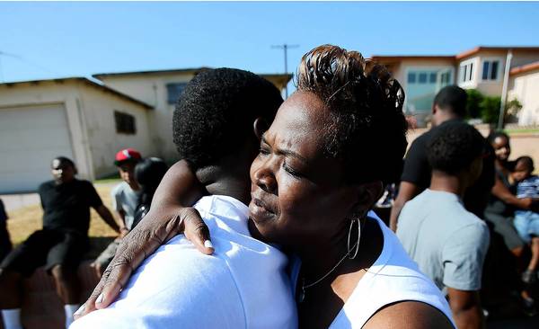 Denise Gatewood, mother of slain Emmanuel Gatewood, embraces relatives and friends who gathered at the site of his death to remember the 17-year-old football player who was killed one year ago.