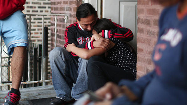 Lazaro Salas, center, who's sister Jasmin Salas was found stabbed to death in a plastic container at a forest preserve in River Forest, comforts her niece, Arianna Salas, on the steps of their family home in Chicago on Oct. 12.