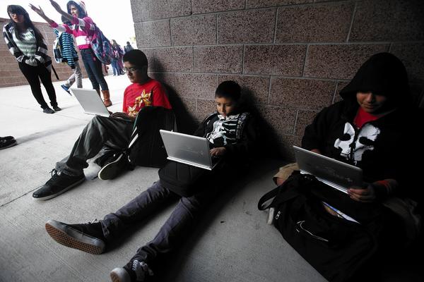 Perris middle school students Jacob Quinino, 13, left, Brian Guereque, 12, and Joshua Ortega, 12, use their Chromebook devices during lunch break.