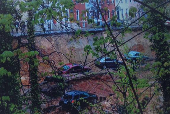 Land and cars rest on train tracks along E. 26th Street in Baltimore's Charles Village Wednesday evening after a regaining wall and the earth gave way. The landslide followed two days of heavy rain in Maryland.