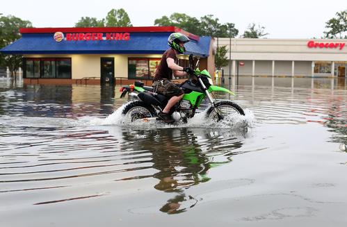 A man rides a motorcycle past a Burger King located on Brent Lane, one of the main roads in the city that was flooded out after heavy rains and flash flooding on April 30, 2014 in Pensacola, Florida.