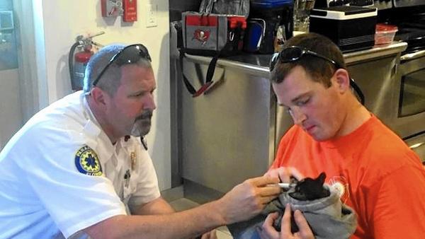 Lake Emergency Medical Services employee Bubba Pitzer, left, Lake County firefighter Luke Brear feed a kitten named Passon.