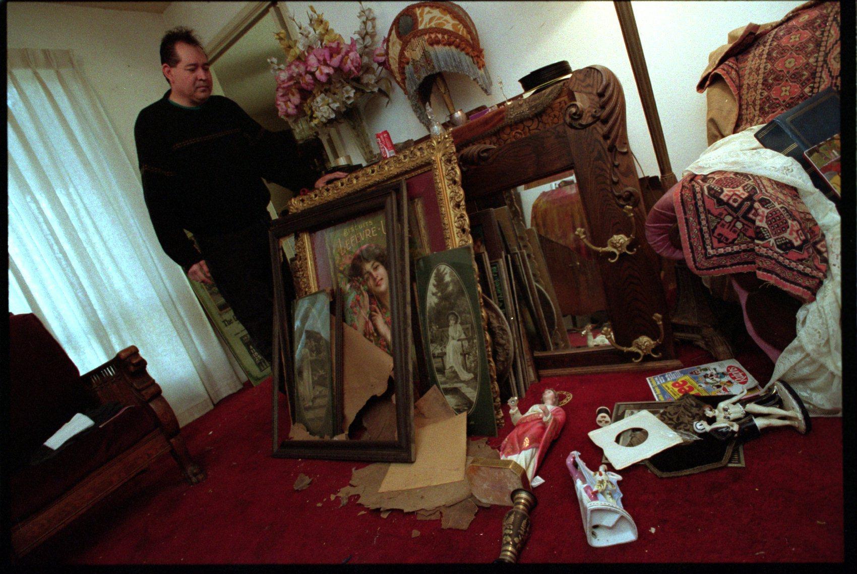 Rick Olguin of Lake View Terrace stands next to rare Victorian paintings from his collection after the 1994 Northridge earthquake. About 50 were damaged in the quake. 