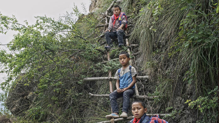 Children carry their school backpacks as they climb a cliff on their way home from school in Zhaojue county, southwest China's Sichuan province.