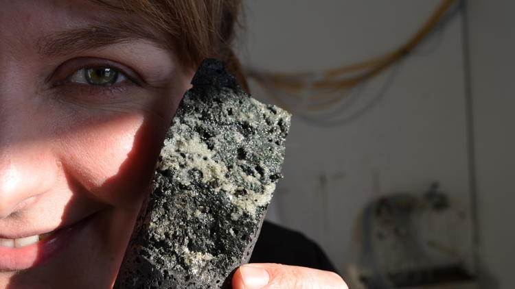 University of Iceland geologist Sandra Snaebjornsdottir holds up a core of porous basalt laced with carbonate minerals, evidence the carbon dioxide injection worked.