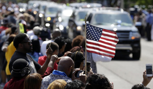 A mourner holds a U.S. flag as the funeral procession for Muhammad Ali makes its way down Muhammad Ali Boulevard. (Michael Conroy / Associated Press)