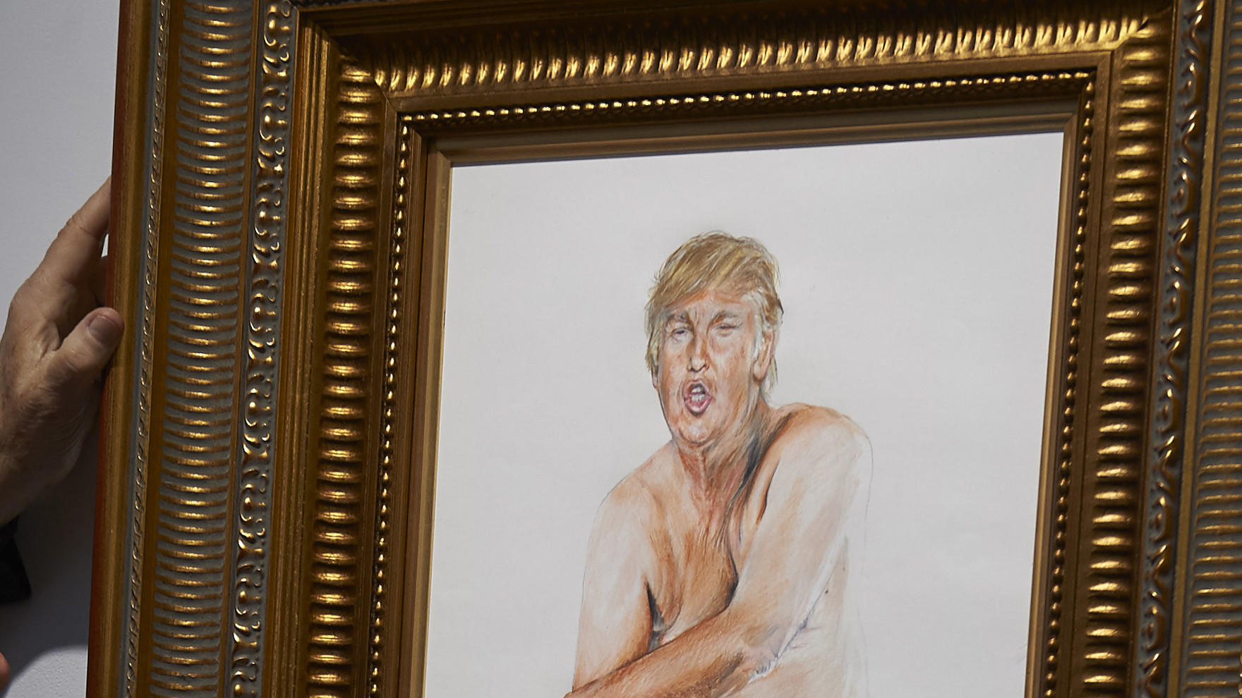 A curator adjusts a painting of Donald Trump by Illma Gore at an exhibition in London.