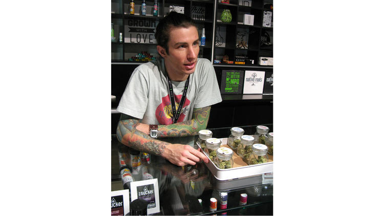 Brandon Pierre Maniez, a bud tender at Native Roots Dispensary in downtown Denver, displays some products for sale.