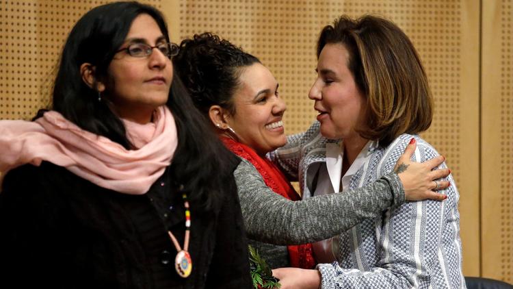 Seattle City Councilwoman Kshama Sawant, left, as fellow Councilwoman Debora Juarez, right, is embraced by Rachel Heaton, a Muckleshoot tribal member, before Wednesday's council meeting.