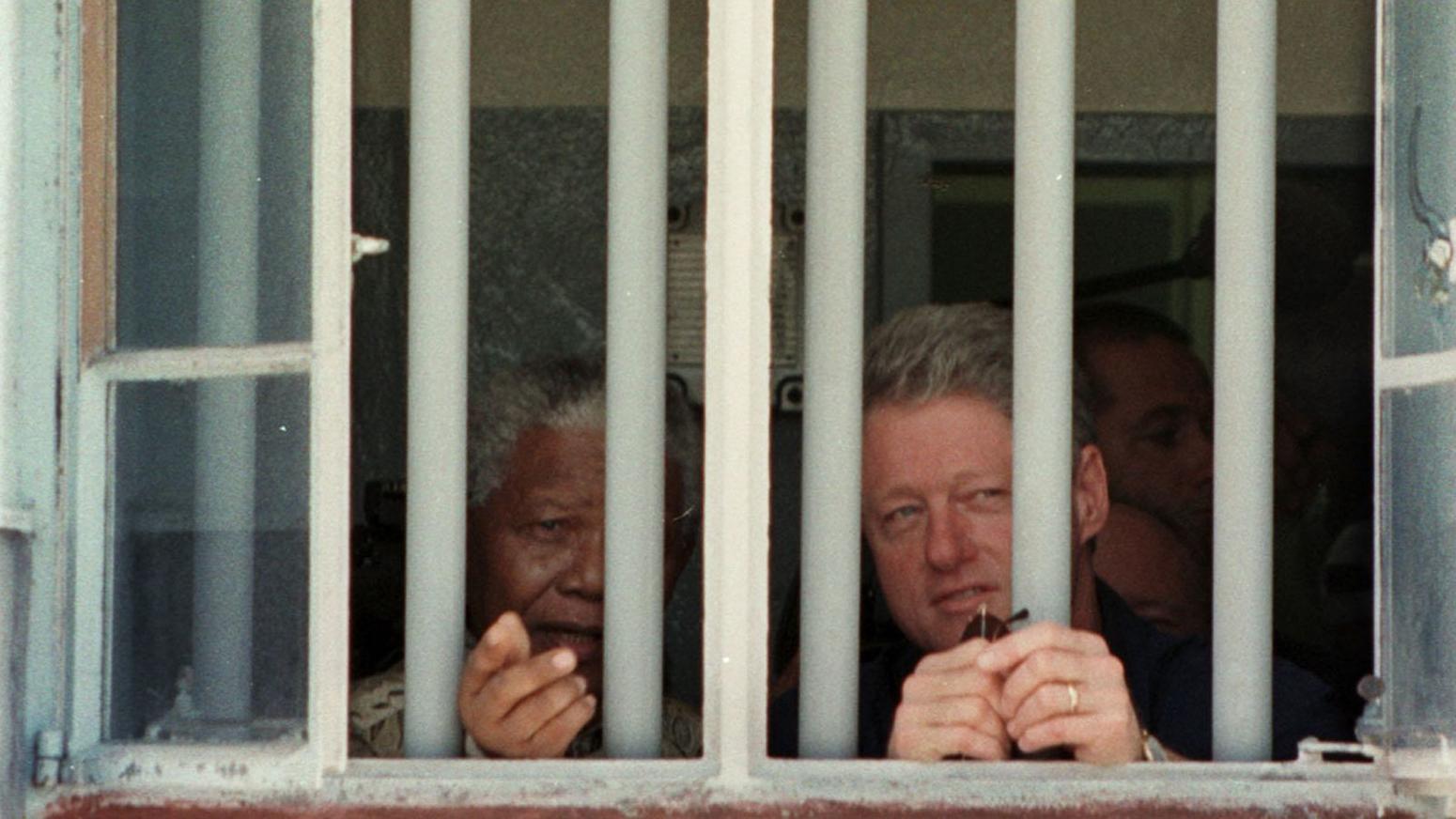 South African President Nelson Mandela and then-U.S. President Bill Clinton peer out of the window of the jail cell at Robben Island, where Mandela spent 18 of the 27 years he was in prison.