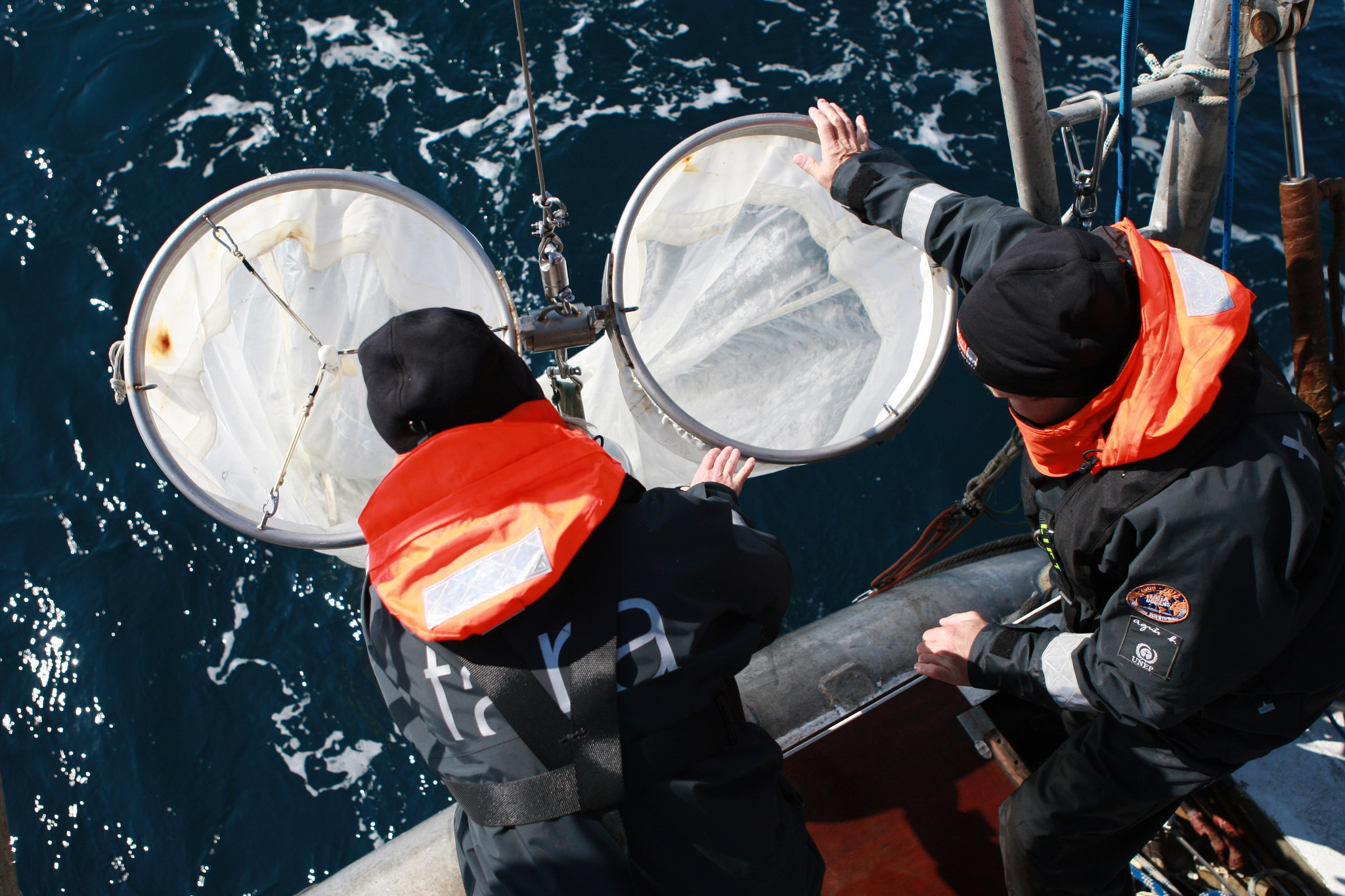 Scientists lower nets into the water to collect plankton and microplastics.