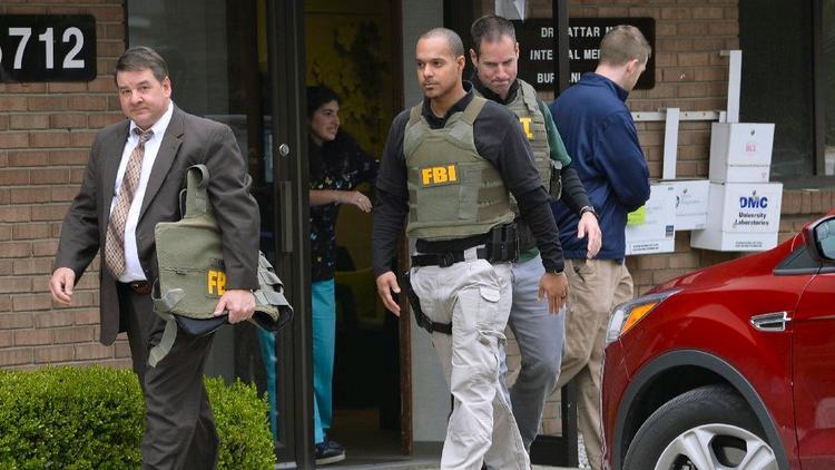 Các sĩ quan FBI rời khỏi phòng khám của bác sĩ Fakhruddin Attar tại Livonia, Mich., vào ngày thứ Sáu sau khi hoàn thành công đoạn thu thập bằng chứng. (Theo Clarence Tabb Jr./ Associated Press)