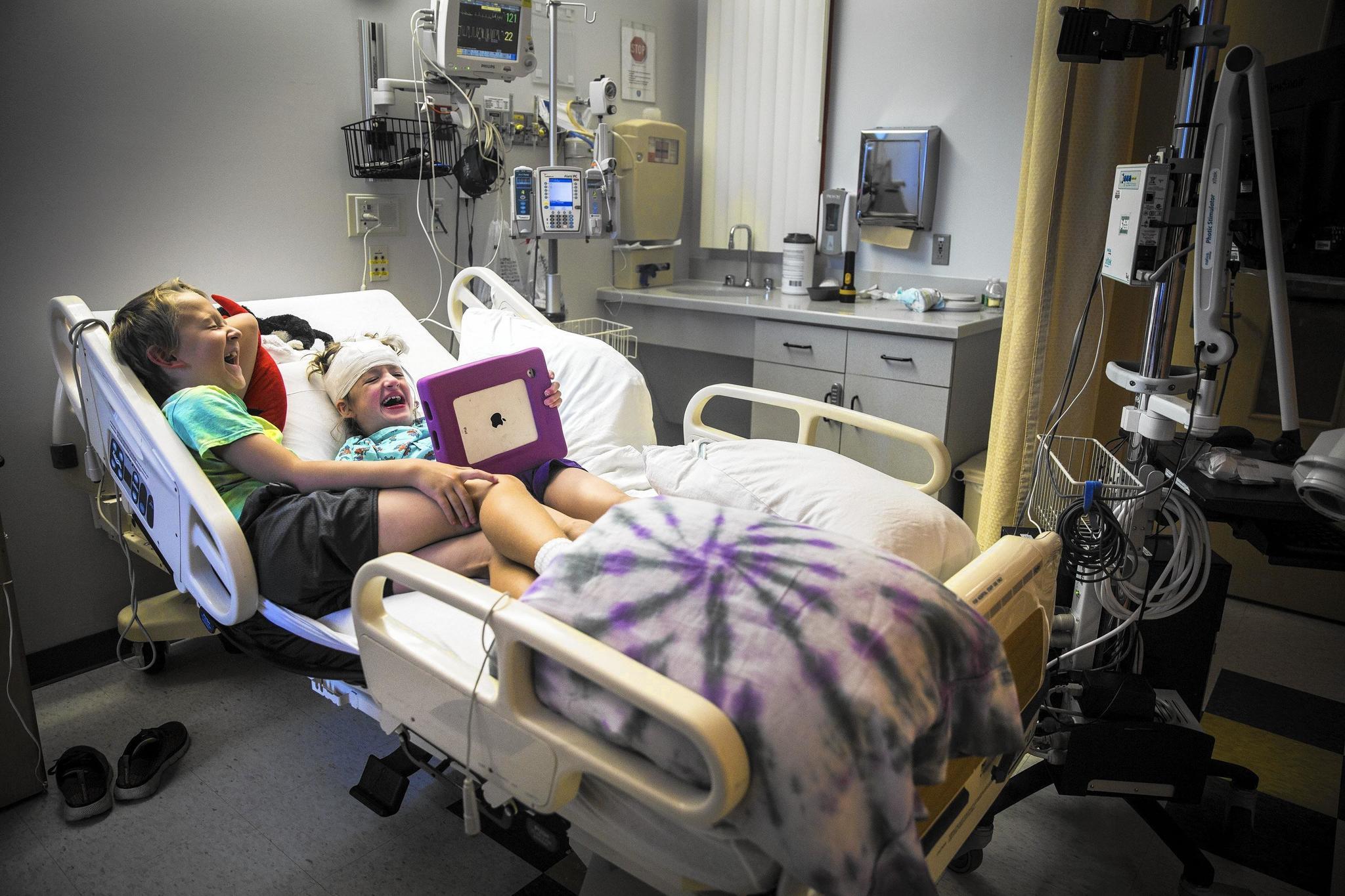 West Tarricone and her twin brother, Blake, watch TV on an iPad in her hospital bed at Connecticut Children