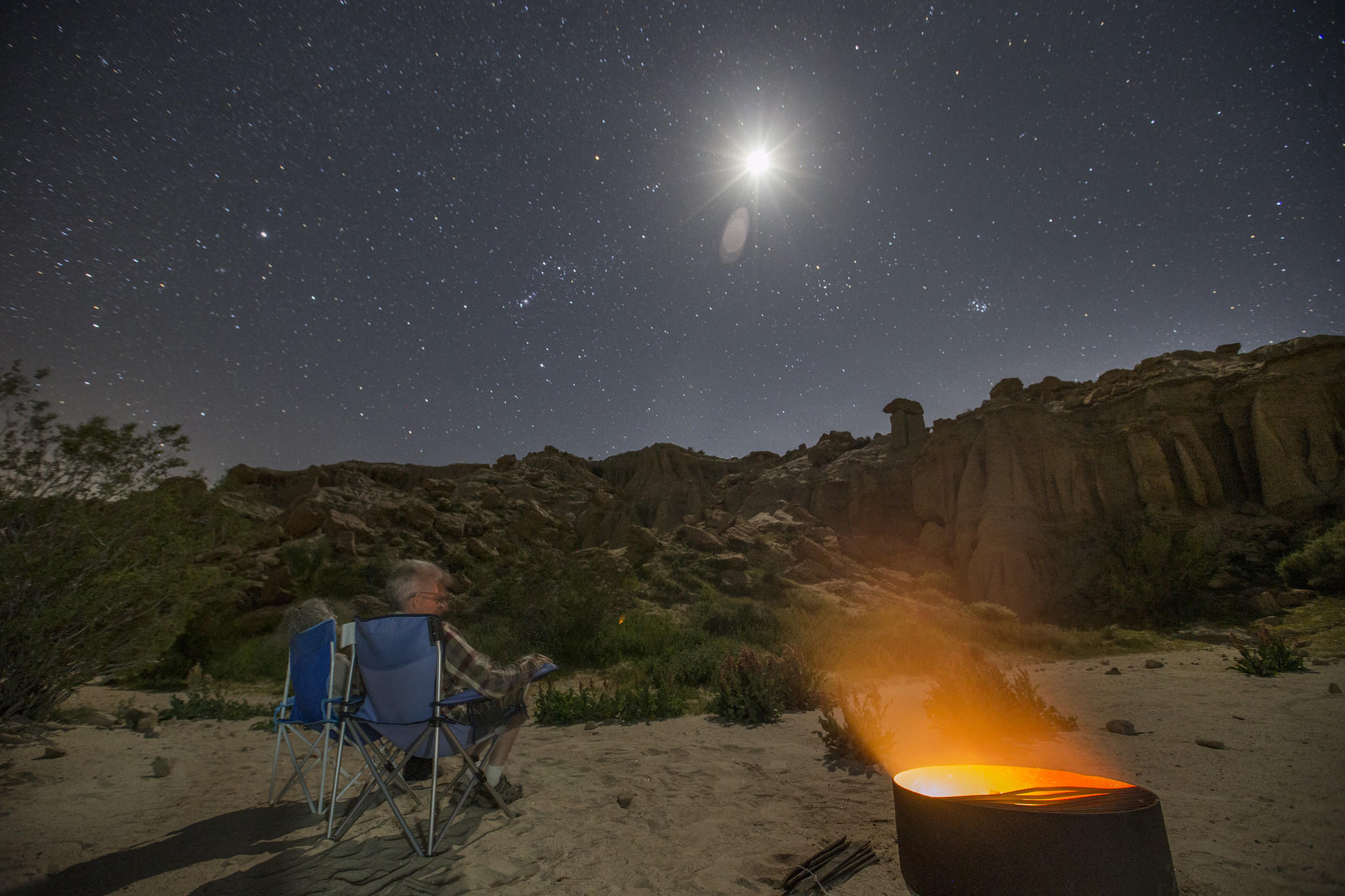 Charles and Julie Fleming check out the stars on a clear night by a campfire at dusk while camping in an Airstream Bambi Sport at Red Rock Canyon Ricardo campground.